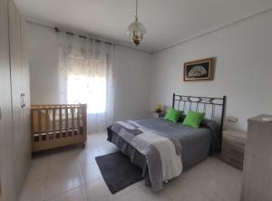 a bedroom with a bed with green pillows and a crib at Casa Quico in Higuera de Arjona