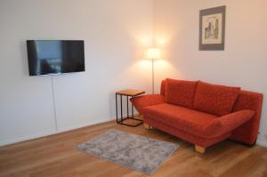 ein Wohnzimmer mit einem roten Stuhl und einem Flachbild-TV in der Unterkunft Ferienwohnung Geng in Überlingen