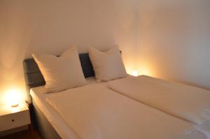 ein weißes Bett mit zwei weißen Kissen darauf in der Unterkunft Ferienwohnung Geng in Überlingen