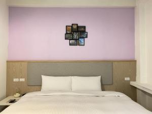 a bedroom with a bed with four pictures on the wall at Meant to Be in Chiayi City