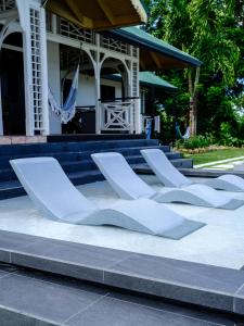 a group of white chairs sitting in front of a building at Silk Cotton Cottages in Parrot Hall