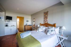 a bedroom with a large white bed and a kitchen at The Spinning Reel Beach Cottages in Port Alfred