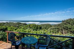 a table and chairs on a deck with the ocean at The Spinning Reel Beach Cottages in Port Alfred