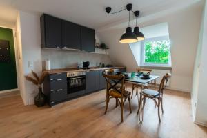 a kitchen with a table and chairs and a kitchen with black cabinets at Rooftop Suite Essen Central-Fair-HBF-Uniklinik-Balcony-Walk-In Shower-Coffee station-WiFi-Workspace in Essen