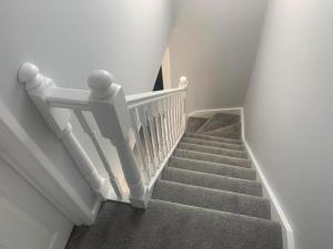 a stairway with a white railing and a stair case at Heaven in Cheam