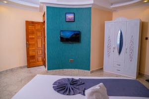 a bedroom with a bed and a tv on a wall at Calfie Resort Kisumu in Ahero