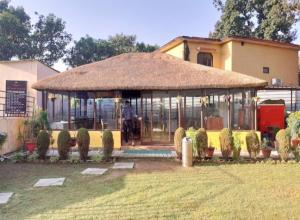 a house with a thatched roof with a man standing in front at Mannat Corbett Resort in Rāmnagar