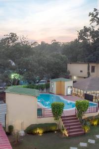 vista para uma piscina ao anoitecer em Mannat Corbett Resort em Rāmnagar