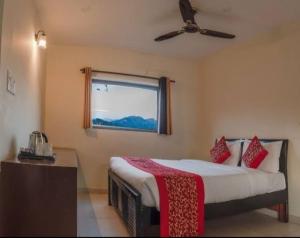 a bedroom with a bed with a ceiling fan and a window at Mannat Corbett Resort in Rāmnagar
