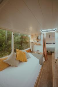 een groot wit bed in een kamer met een raam bij The Amazing Inácio Bus converted home in Sintra