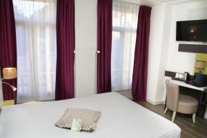 um quarto de hotel com uma cama com cortinas vermelhas em Grand Hôtel Lille em Lille