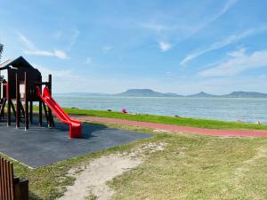 een speeltuin met een rode glijbaan naast het water bij Balaton lake view 30 m from Beach in Fonyód