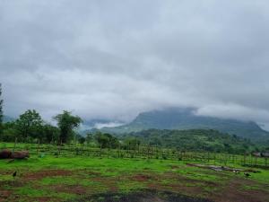 a field with a fence and a mountain in the background at Raje Bhosale Farm in Ghātgarh