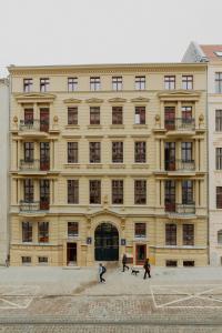 un gran edificio amarillo con gente delante de él en The Bank Poznan Apartments, en Poznan