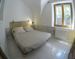 a small bed in a room with a window at Appartement en pierre à proximité Lourmarin in Lauris