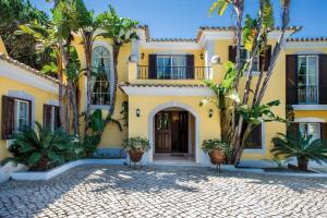una casa amarilla con palmeras delante en Villa Plaza - beautiful spacious house off roundabout 6 Quinta Do Lago en Quinta do Lago