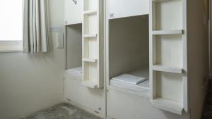 a walk in closet with white shelves and a mirror at almond hostel & cafe Shibuya in Tokyo