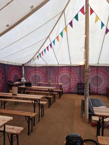 Tienda con mesas y banderas en una habitación en Glamping at Hay Festival en Hay-on-Wye