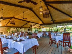 un comedor con mesas y sillas blancas en Insika lodge en Victoria Falls