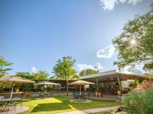 a patio with tables and chairs and umbrellas at Insika lodge in Victoria Falls