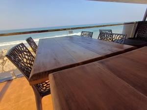 une table et des chaises en bois avec l'océan en arrière-plan dans l'établissement East West Beach Resorts, à Varkala