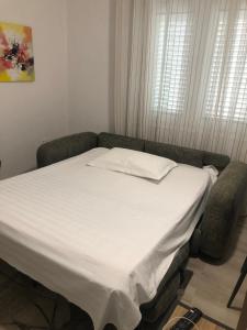 a bed in a room with a white bedsheet at Brilant Apartament in Tirana