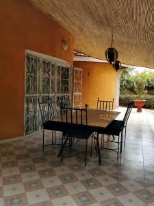 uma sala de jantar com uma mesa de madeira e cadeiras em Maison d'hôte à la Somone em Somone