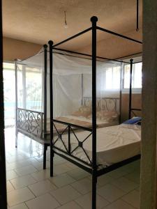 um quarto com uma cama de dossel com lençóis brancos em Maison d'hôte à la Somone em Somone