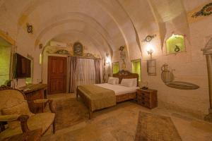 um quarto com uma cama e uma cadeira num quarto em Capp Royal Cave HOTEL em Ürgüp