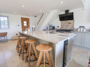 a kitchen with a counter with stools around it at The Shippon in Frodsham