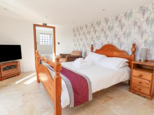 a bedroom with a wooden bed and a television at The Shippon in Frodsham