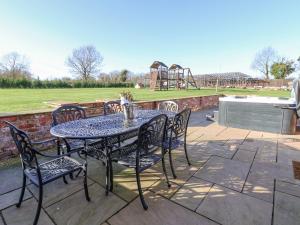 una mesa y sillas en un patio con parque infantil en The Shippon en Frodsham