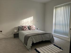 a white bedroom with a bed with pink pillows at Delightful & Spacious Flat in London - Peckham in London