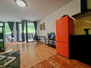 - un salon avec un réfrigérateur orange et une table dans l'établissement Pamporovo Studio Five, à Pamporovo