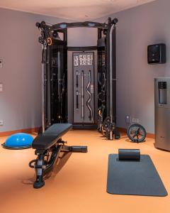 a room with a gym with a bench and weights at URBAN LOFT Cologne in Cologne