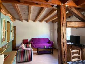 sala de estar con sofá púrpura y TV en Entre Lacs et Sapins en Dortan