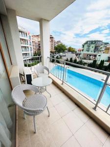 a balcony with two chairs and a table and a pool at Sun Wave Sea and Pool View in Sveti Vlas