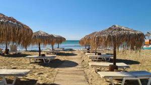 a row of straw umbrellas and chairs on a beach at Sun Wave Sea and Pool View in Sveti Vlas