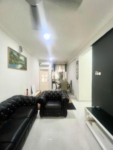 uma sala de estar com um sofá de couro preto e uma televisão em TP Homestay2 em Kuala Terengganu