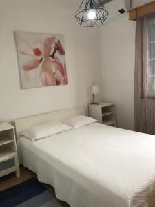 a bedroom with a white bed and a painting on the wall at Casa da Fajã in Ponta Delgada