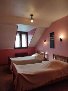 two beds in a room with pink walls at hotel de l'ain in Pont-de-Poitte