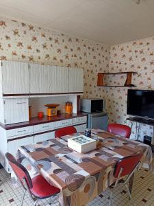 eine Küche mit einem Tisch mit Stühlen und einem TV in der Unterkunft Appartement en Bresse 