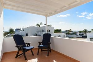 2 Stühle auf einem Balkon mit Stadtblick in der Unterkunft Villa Golf Lanzarote in Costa Teguise