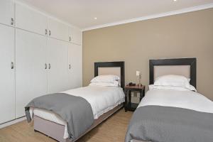two beds in a bedroom with white cabinets at Pinnacle Point Heritage Villa in Mossel Bay +21 photos