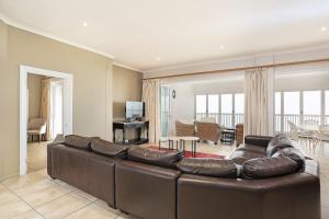 a living room with a large brown leather couch at Pinnacle Point Heritage Villa in Mossel Bay