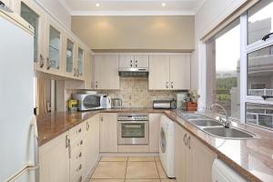 a kitchen with white cabinets and a sink and a window at Pinnacle Point Heritage Villa in Mossel Bay