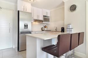 a white kitchen with a counter and a refrigerator at The Paragon 317 by HostAgents in Cape Town