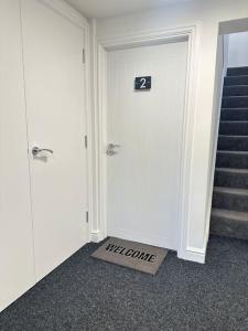 a hallway with a door with a sign that says welcome at Spacious and Stylish Flat in Trowbridge, Wiltshire in Trowbridge