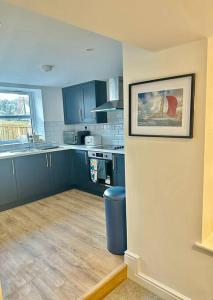 a kitchen with blue cabinets and a picture on the wall at Spacious and Stylish Flat in Trowbridge, Wiltshire in Trowbridge