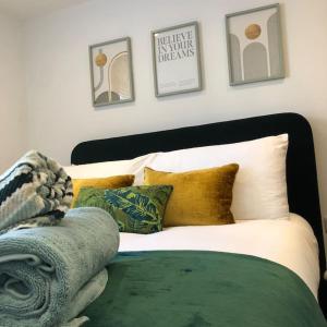 um quarto com uma cama com almofadas e fotografias na parede em Spacious and Stylish Flat in Trowbridge, Wiltshire em Trowbridge